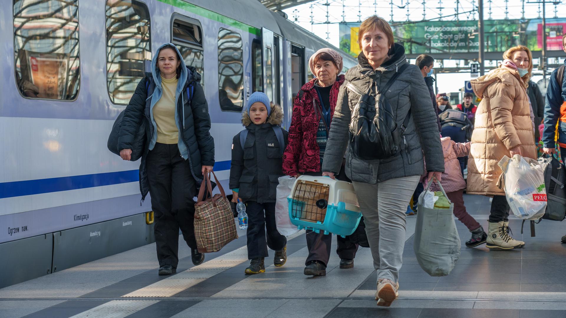 Geflüchtete Menschen aus der Ukraine bei der Ankunft am Berliner Hauptbahnhof. Sie tragen unter anderem Taschen und eine Haustier-Transportbox.