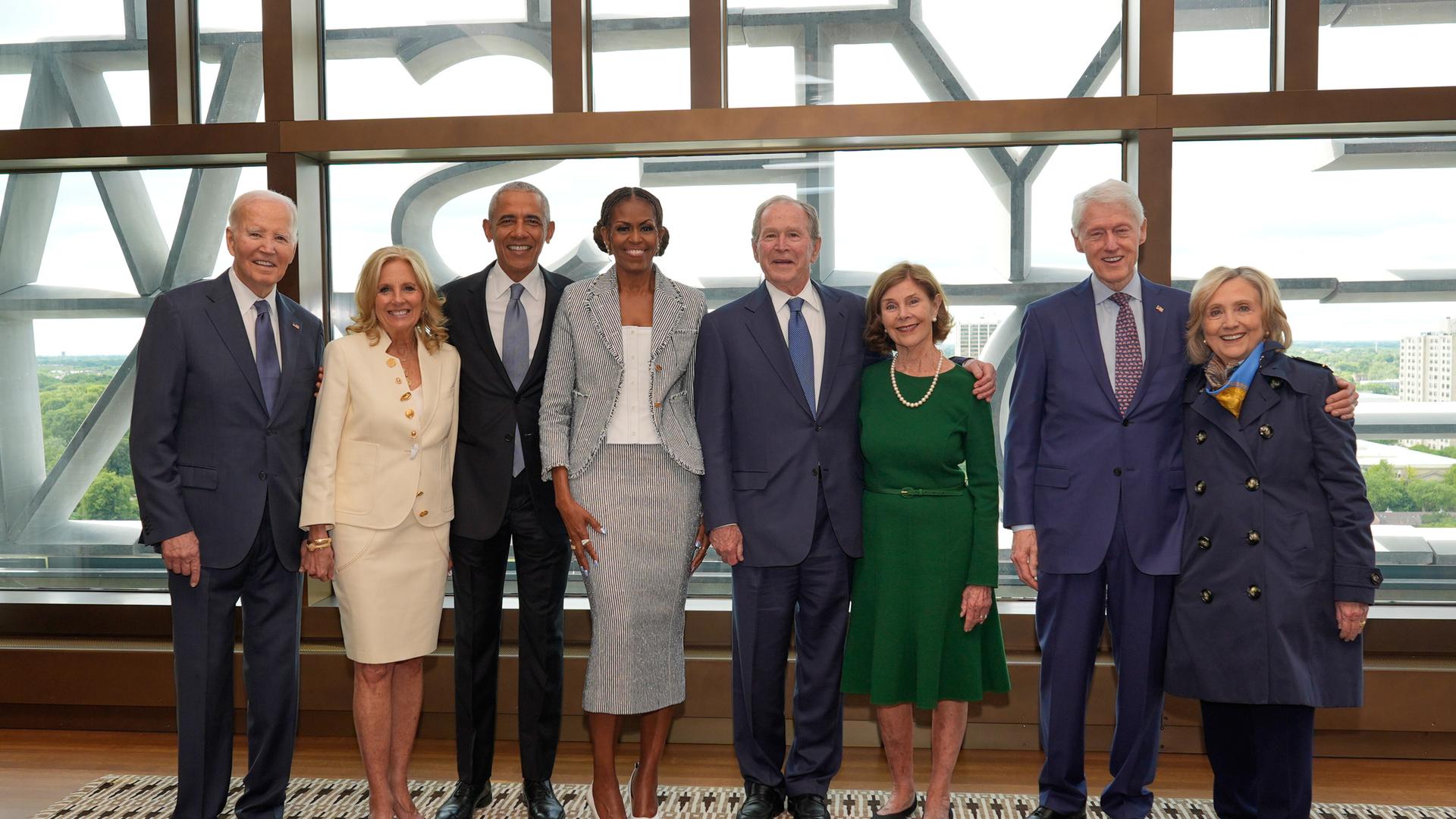 Acht Menschen stehen nebeneinander: Joe Biden, Jill Biden, Barack Obama, Michelle Obama, George W. Bush, Laura Bush, Bill Clinton und Hillary Clinton. Acht Menschen stehen nebeneinander: Joe Biden, Jill Biden, Barack Obama, Michelle Obama, George W. Bush, Laura Bush, Bill Clinton und Hillary Clinton.