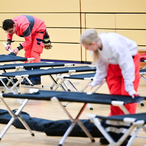 Ehrenamtliche Mitarbeiter des Roten Kreuzes bauen während eines Stromausfalls im Südwesten Berlins in einer Notunterkunft Feldbetten auf.