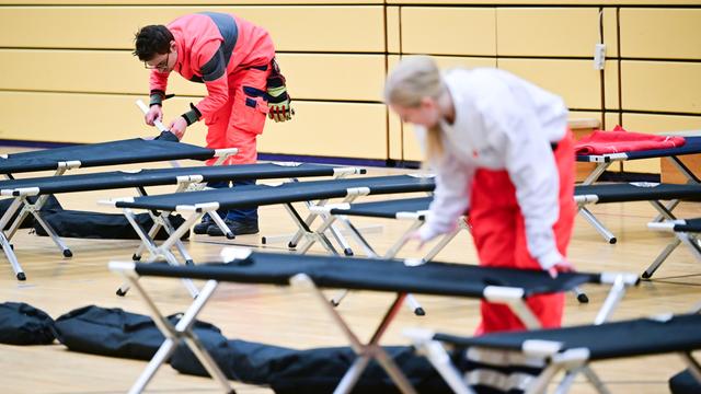Ehrenamtliche Mitarbeiter des Roten Kreuzes bauen während eines Stromausfalls im Südwesten Berlins in einer Notunterkunft Feldbetten auf.