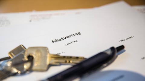 Auf dem Tisch liegt ein Mietvertrag für eine Mietswohnung und die Schlüssel für die Wohnungstüren.