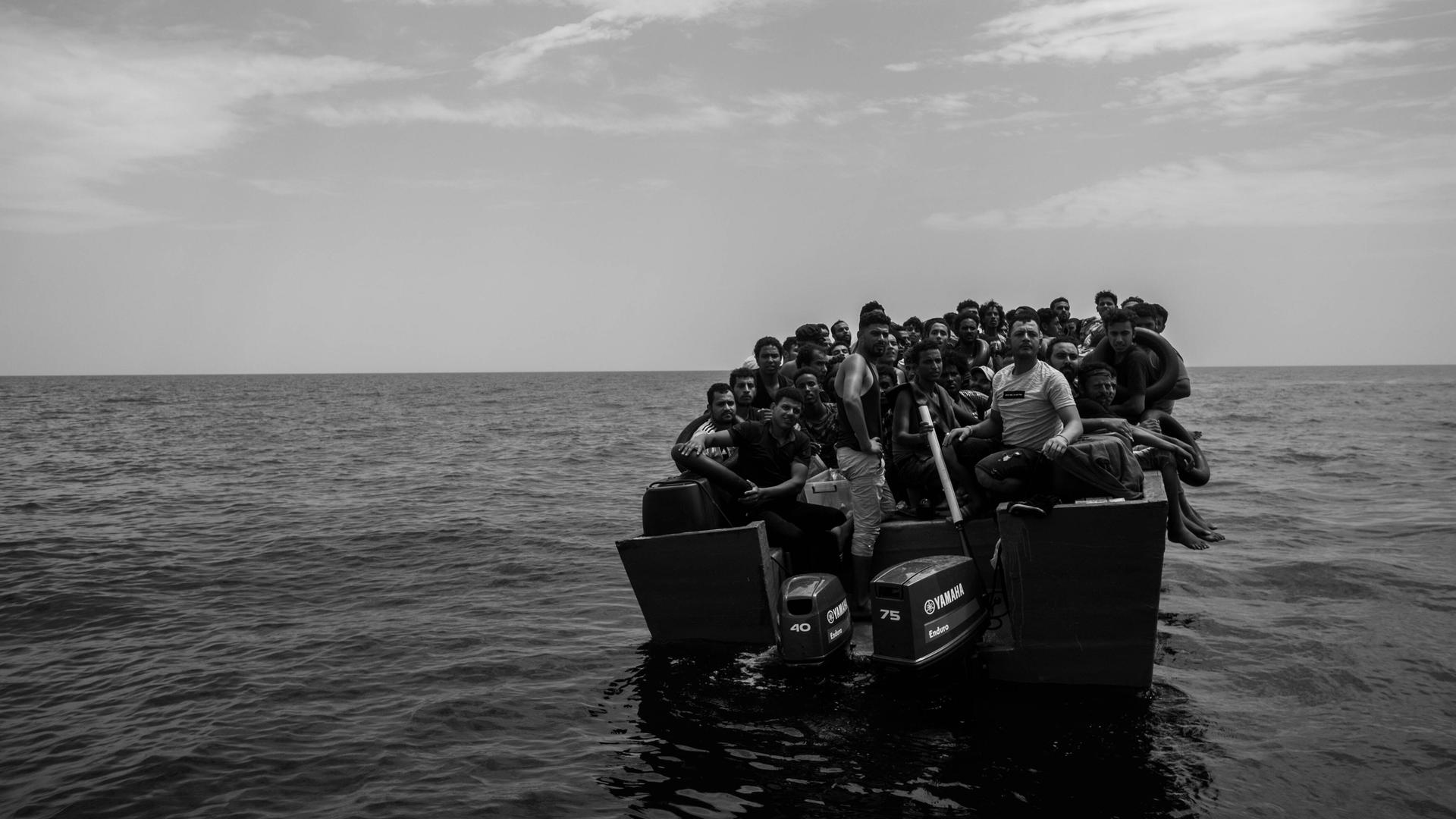 Aus Libyen flüchtende Menschen treiben auf einem Boot im Mittelmeer. 