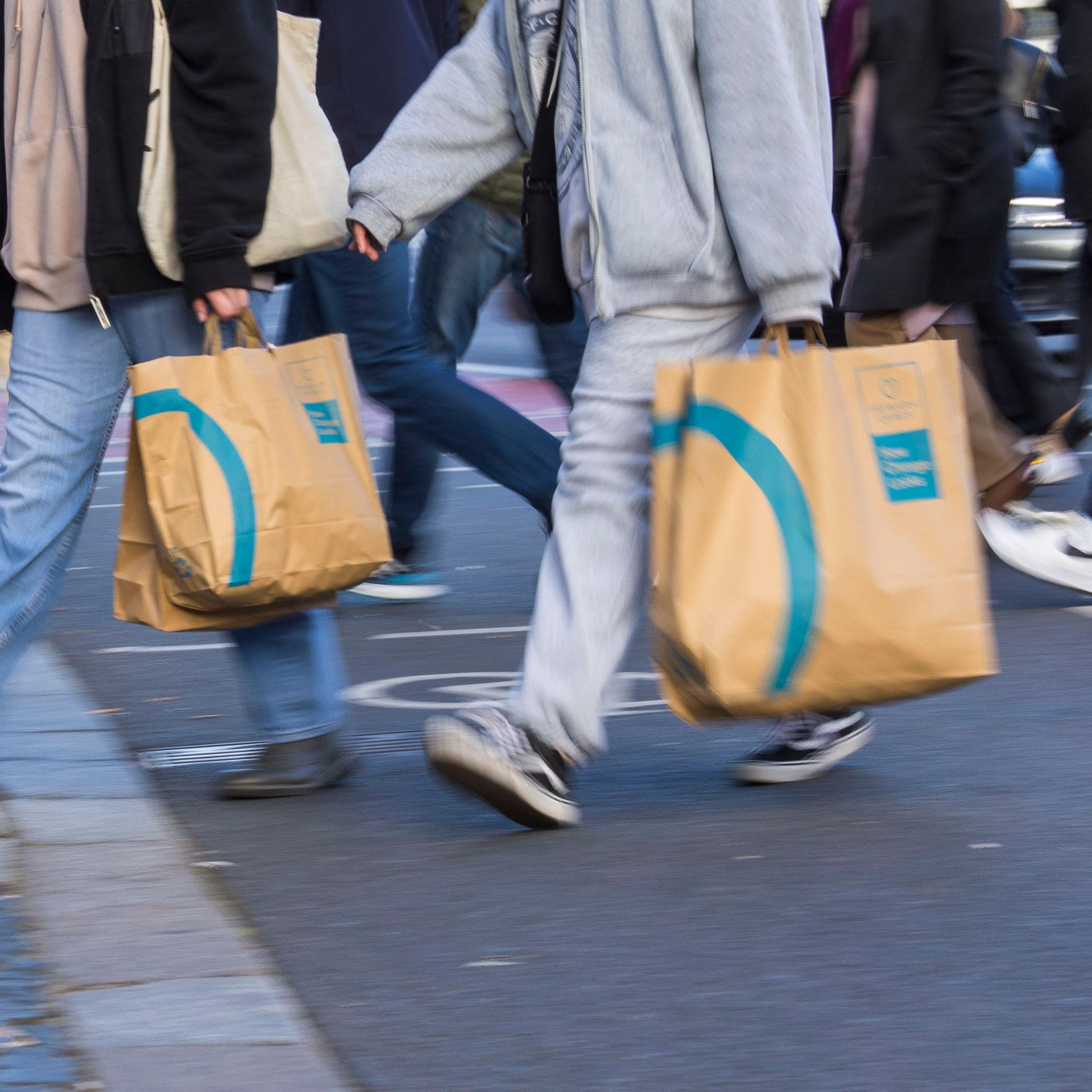 Passanten tragen Einkaufstaschen beim Überqueren der Strasse