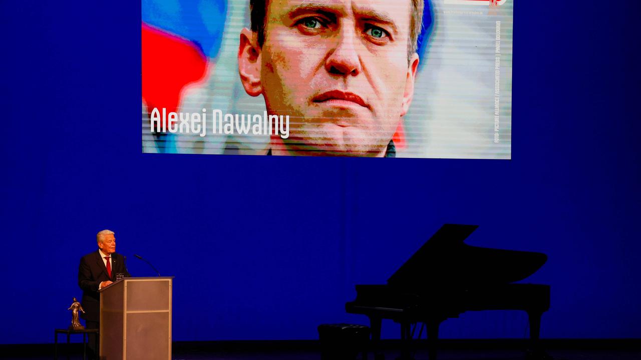 Alexej Nawalny wird postum mit dem Friedenspreis Dresden ausgezeichnet. Alt-Bundeskanzler Gauck steht an einem Podest auf der Bühne, hinter ihm an der Wand ein Bild von Nawalny.