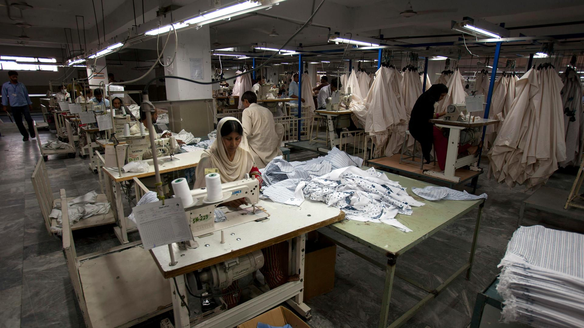 Arbeiterin in einer Textilfabrik in Pakistan, in der die Stromversorgung nur reduziert läuft. 