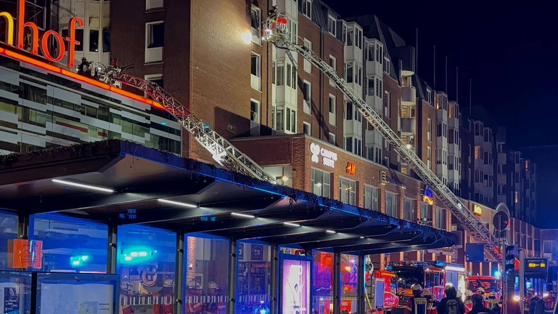 Einsatzkräfte der Feuerwehr arbeiten auf Drehleitern vor Balkonen eines Wohnhaus-Komplexes. 