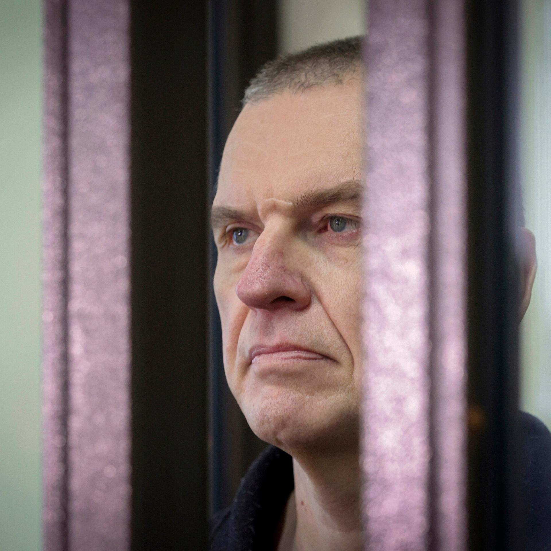 Der inhaftierte belarussische Journalist Andrzej Poczobut im Seitenporträt hinter einem Gitter.