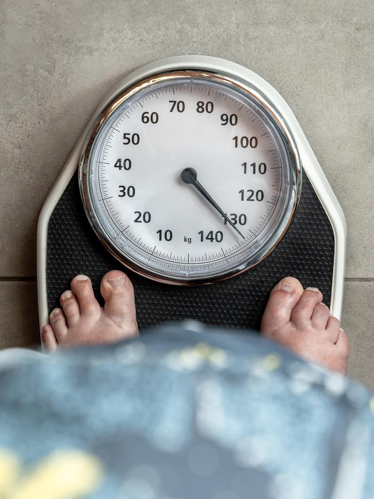 Eine erwachsene Frau steht barfuß auf einer Personenwaage, der Zeiger liegt über 130 kg. Eine erwachsene Frau steht barfuß auf einer Personenwaage, der Zeiger liegt über 130 kg.
