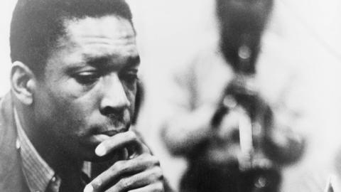 Schwarzweißaufnahme von John Coltrane, der sich nachdenklich die Hand ans Kinn hält Schwarzweißaufnahme von John Coltrane, der sich nachdenklich die Hand ans Kinn hält