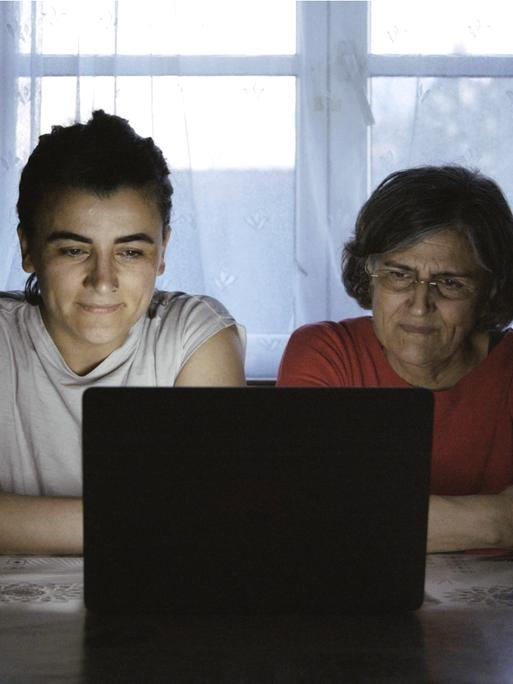Tochter und Mutter sitzen gemeinsam am Abend vor einem Laptop, ein Filmstill aus dem Dokumentarfilm "Exil never ends".