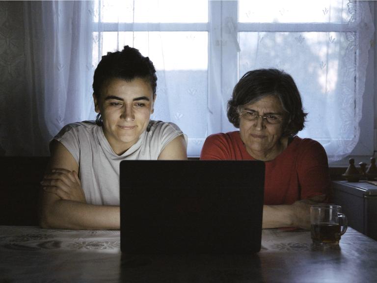 Tochter und Mutter sitzen gemeinsam am Abend vor einem Laptop, ein Filmstill aus dem Dokumentarfilm "Exil never ends".