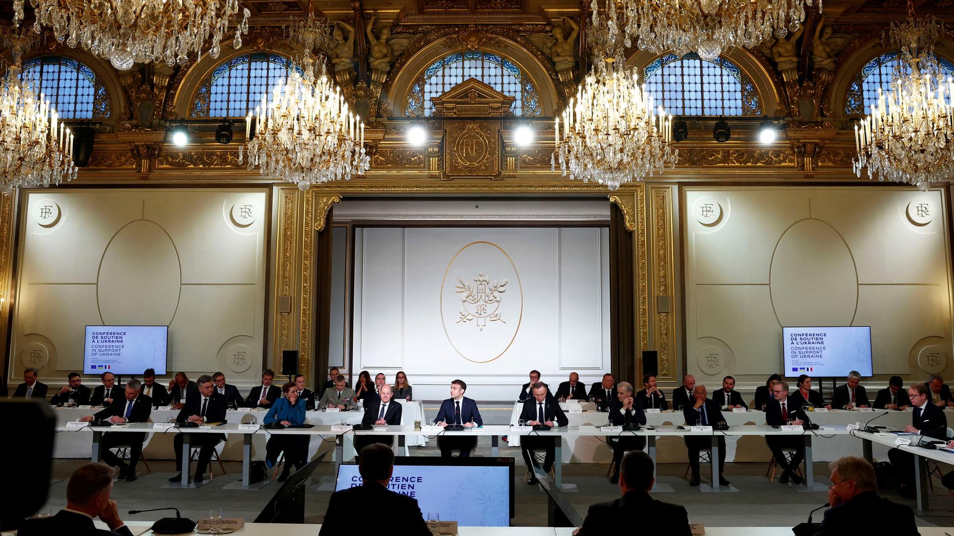 Frankreich, Paris: Emmanuel Macron (M.), Präsident von Frankreich, hält eine Rede im Elysee-Palast. Neben ihm sitzt Bundeskanzler Olaf Scholz (SPD).