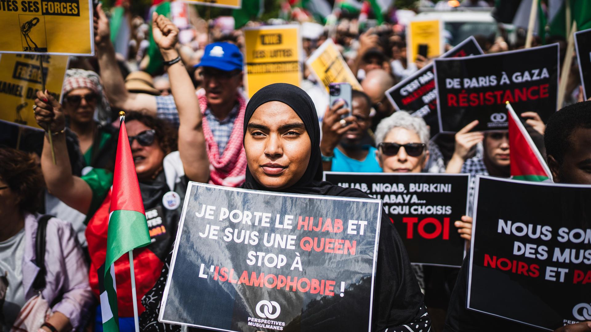 Eine junge Demonstrantin mit Kopftuch hält ein Schild mit der Aufschrift „Ich trage den Hijab und bin eine Königin, stoppt Islamophobie, muslimische Perspektiven“, während einer Demonstration gegen Islamophobie.
Eine junge Demonstrantin mit Kopftuch hält ein Schild mit der Aufschrift „Ich trage den Hijab und bin eine Königin, stoppt Islamophobie, muslimische Perspektiven“, während einer Demonstration gegen Islamophobie.