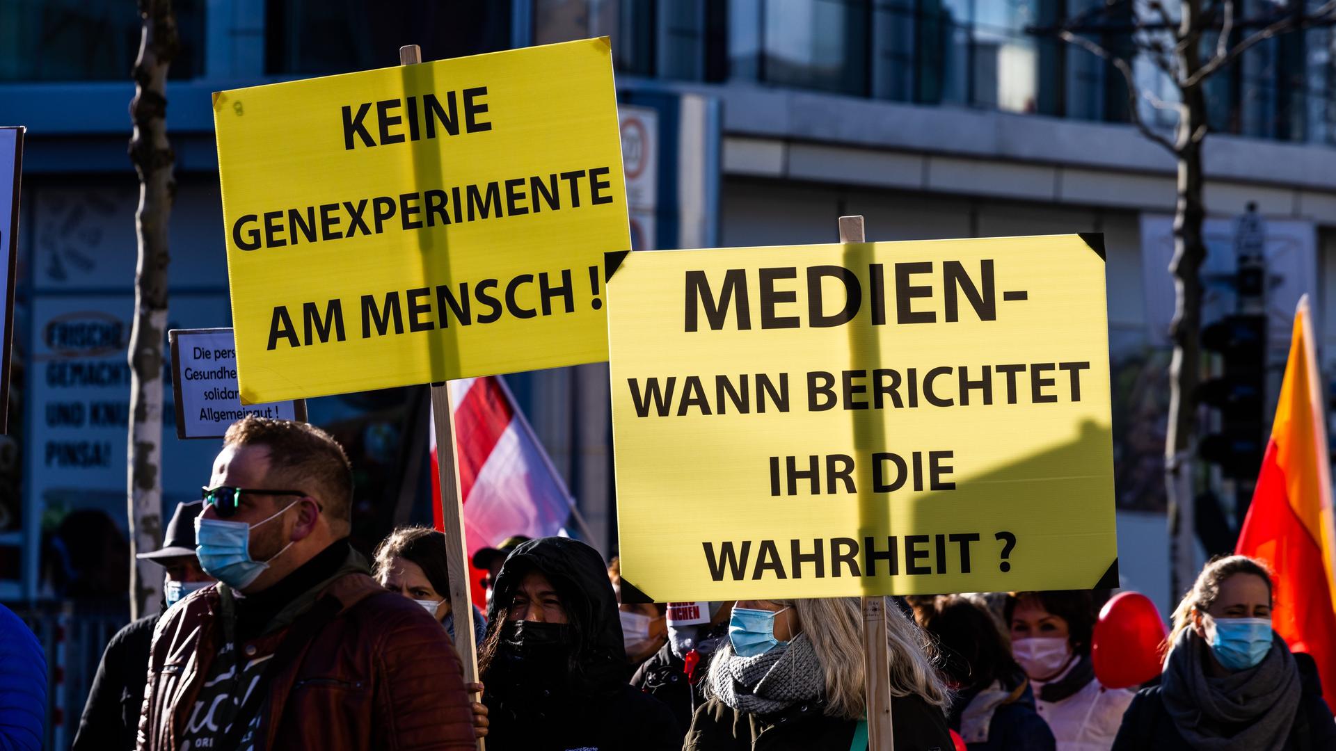 Die Teilnehmer einer Demonstration gegen die Corona-Maßnahmen gehen den Friedrichring entlang und halten Schilder mit den Aufschriften "Keine Genexperimente am Mensch!" und "Medien - wann berichtet ihr die Wahrheit?" in der Hand.