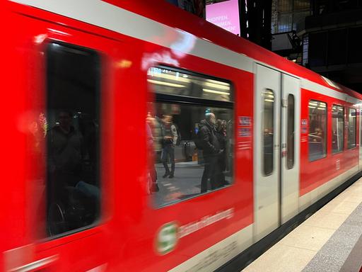 Eine rote S-Bahn fährt am Gleis ab.