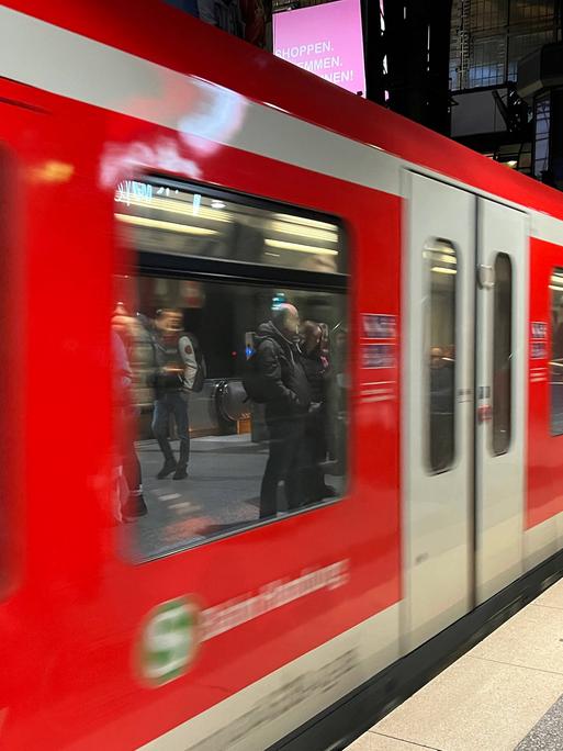 Eine rote S-Bahn fährt am Gleis ab.