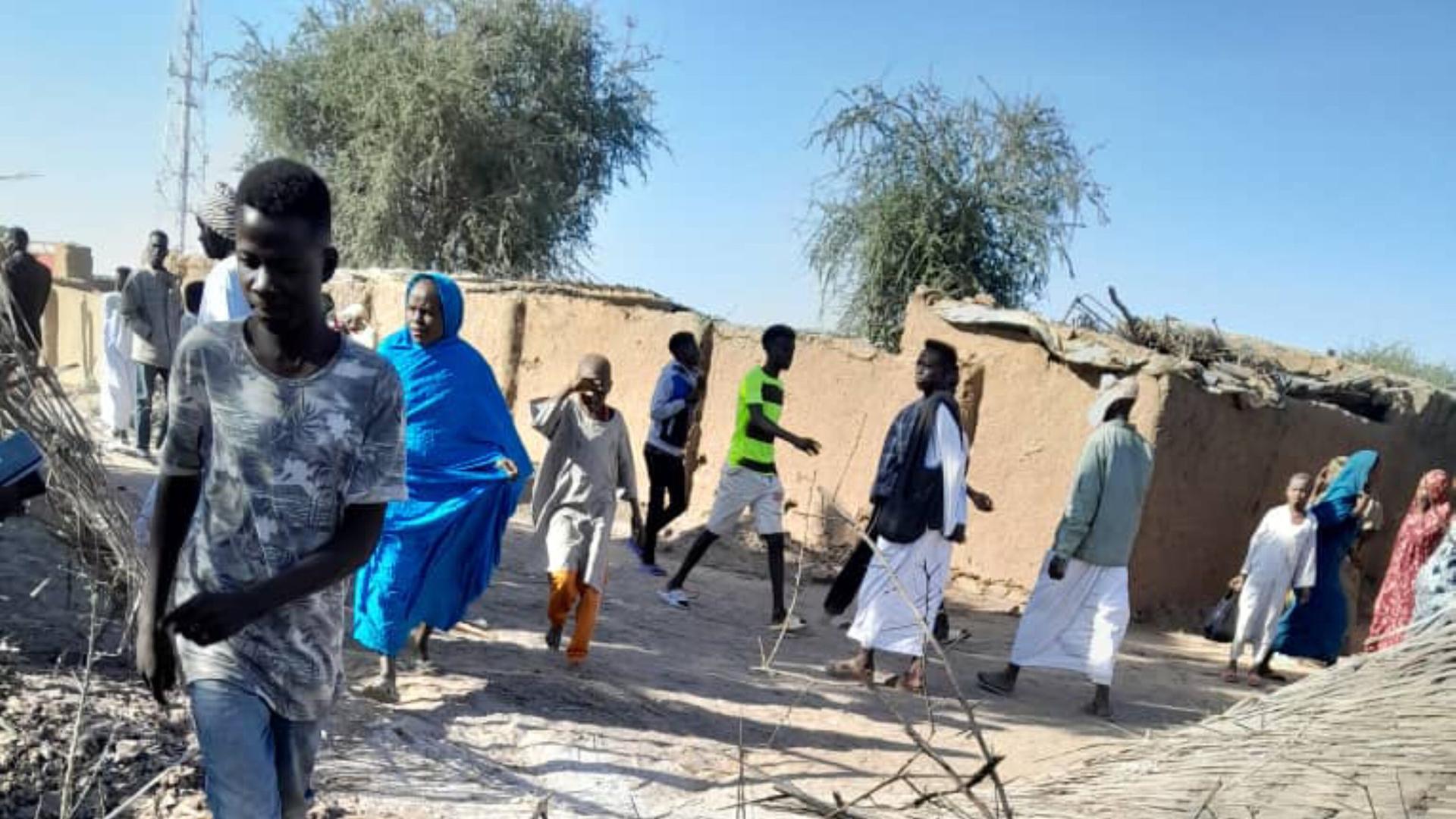 Mehrere Menschen gehen an einer Stelle in Al-Faschir vorbei, an dem ein Anschlag verübt wurde. 