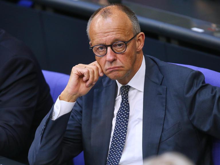 Bundeskanzler Friedrich Merz (CDU) sitzt mit heruntergezogenen Mundwinkeln im Bundestag.
