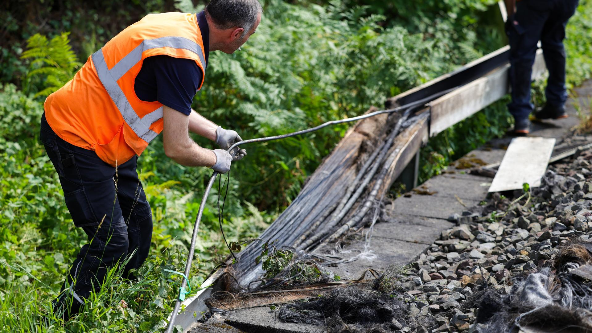 Mitarbeiter der Deutschen Bahn arbeiten an einem Gleisabschnitt in Düsseldorf. Dort wurde neben der Bahnstrecke Feuer in einem Kabeltunnel gelegt, der sechs Kabel in Mitleidenschaft zog. 
