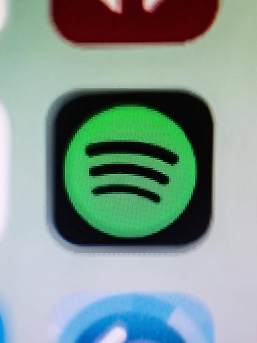 Das Bild zeigt einen kleinen Ausschnitt eines Smartphone-Bildschirms, auf dem drei App-Icons zu sehen sind. Die mittler App ist das Logo von Spotify.