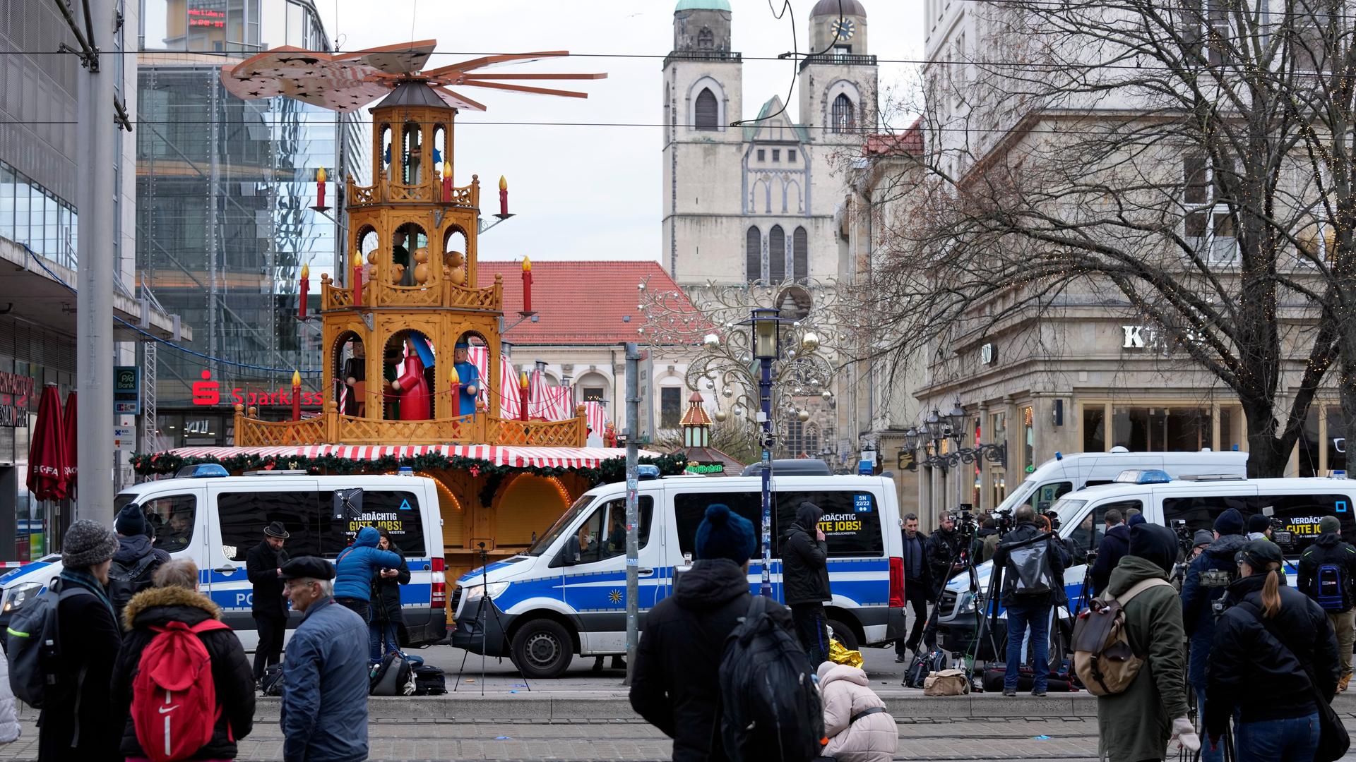 Journalisten stehen in Magdeburg in der Nähe eines abgesperrten Bereichs des Weihnachtsmarktes.
      