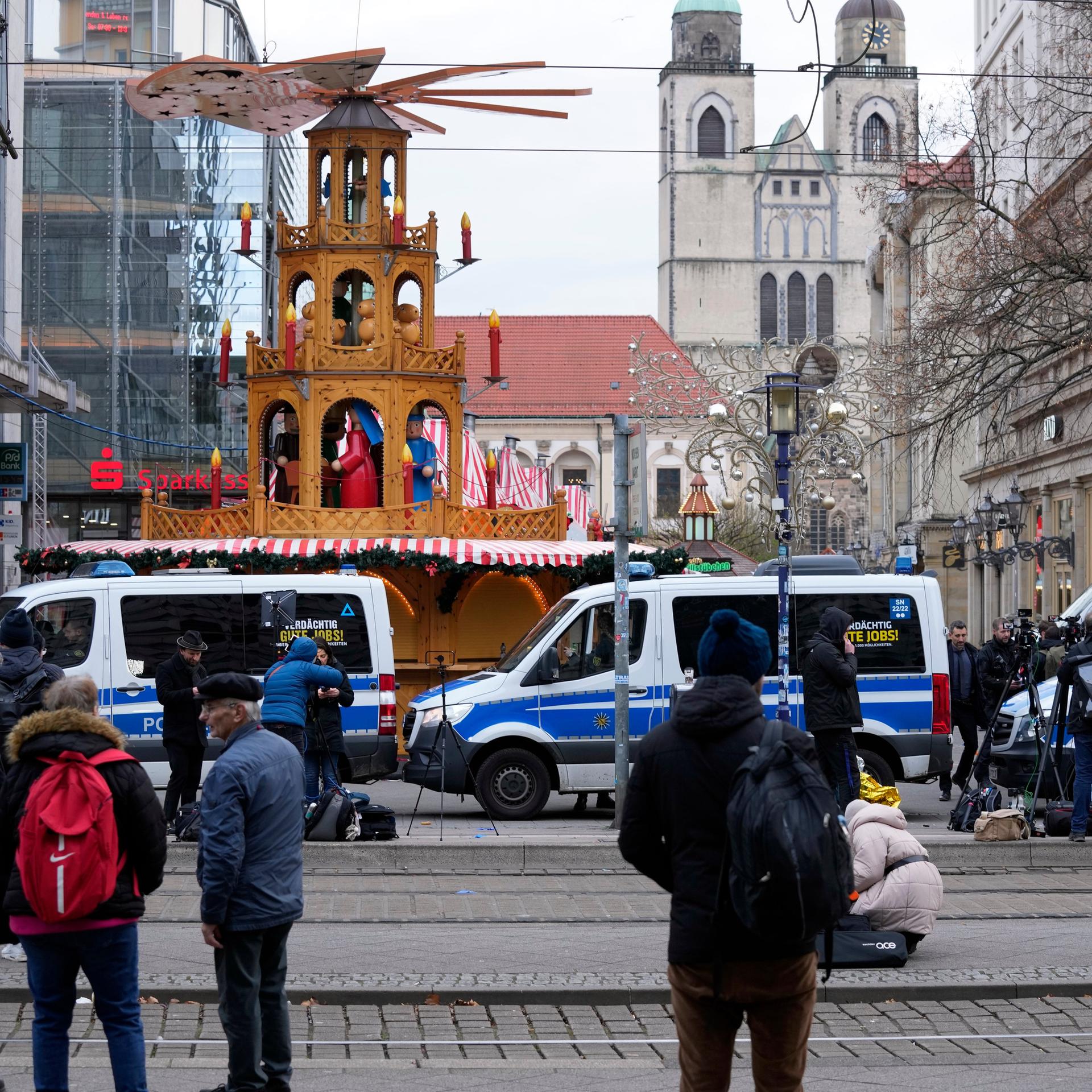 Journalisten stehen in Magdeburg in der Nähe eines abgesperrten Bereichs des Weihnachtsmarktes.
