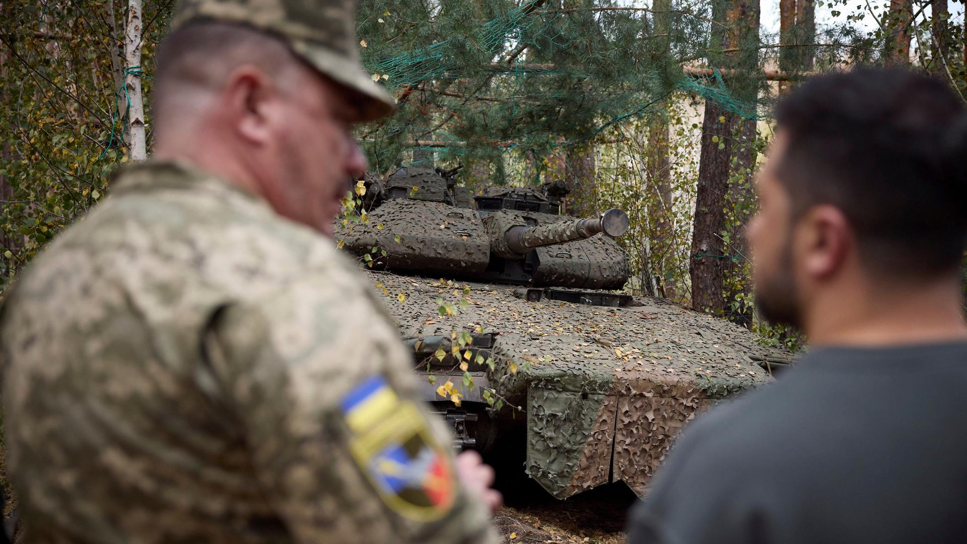 Bei einem Frontbesuch des urainischen Präsidenten ist im Hintergrund ein deutscher Leopard Panzer zu sehen.