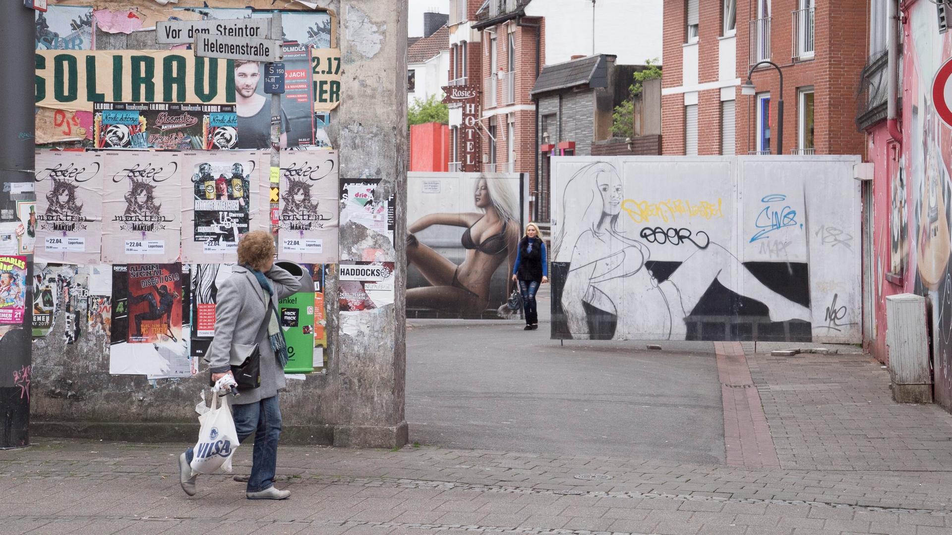 Man sieht den Eingang zur Rotlichtmeile Helenenstrasse in Bremen, im Hintergrund Graffitis von Frauen in Unterwäsche, im Vordergrund eine Frau mit Einkaufstüte Man sieht den Eingang zur Rotlichtmeile Helenenstrasse in Bremen, im Hintergrund Graffitis von Frauen in Unterwäsche, im Vordergrund eine Frau mit Einkaufstüte