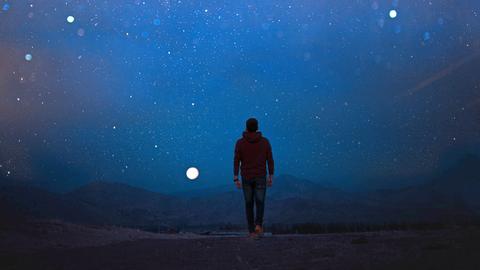 Ein neues humanes Wesen soll den Planeten wiederbesiedeln. Zu sehen: Ein Mann, mit dem Rücken zur Kamera, geht im Dunkeln in einer einsamen Landschaft dem Vollmond entgegen.