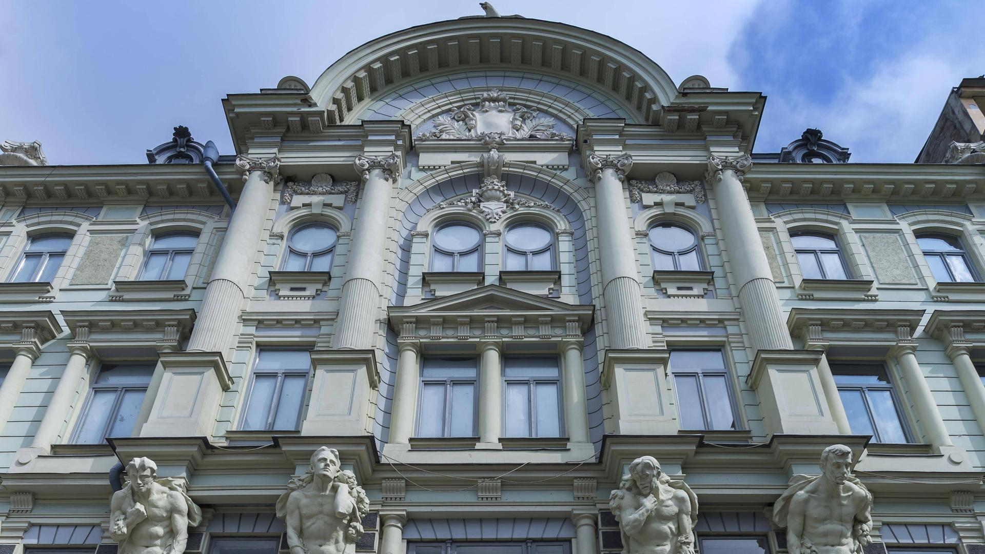Eine Hausfassade aus dem frühen 20. Jahrhundert mit Säulen und Skulpturen.