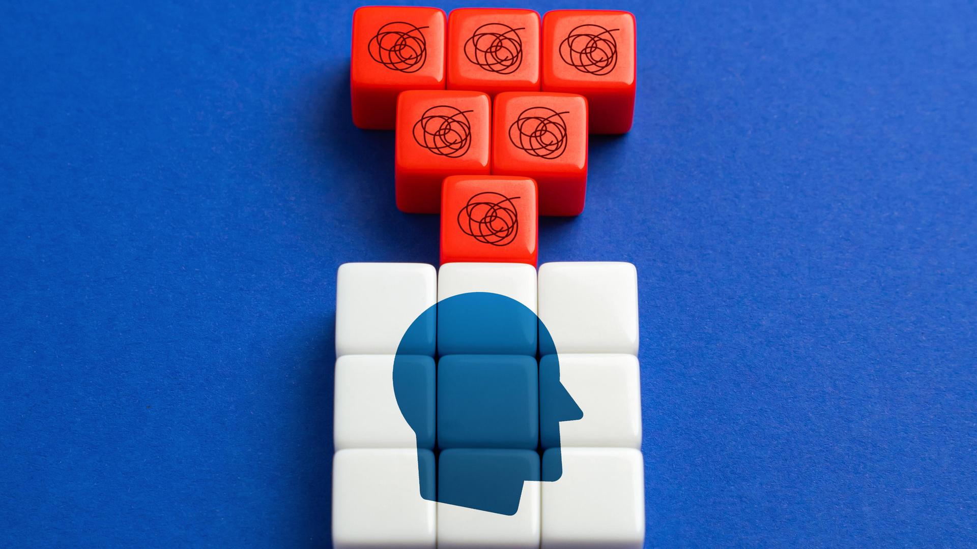 Eine Grafik zum Thema Selbstzweifel Bausteine zeigen einen Kopf. Darüber sind rote Bausteine mit Fragezeichen. 