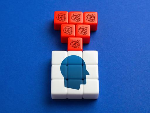 Eine Grafik zum Thema Selbstzweifel Bausteine zeigen einen Kopf. Darüber sind rote Bausteine mit Fragezeichen. 