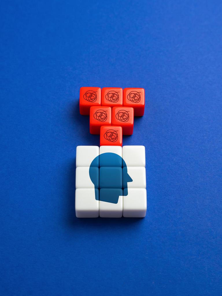 Eine Grafik zum Thema Selbstzweifel Bausteine zeigen einen Kopf. Darüber sind rote Bausteine mit Fragezeichen. 