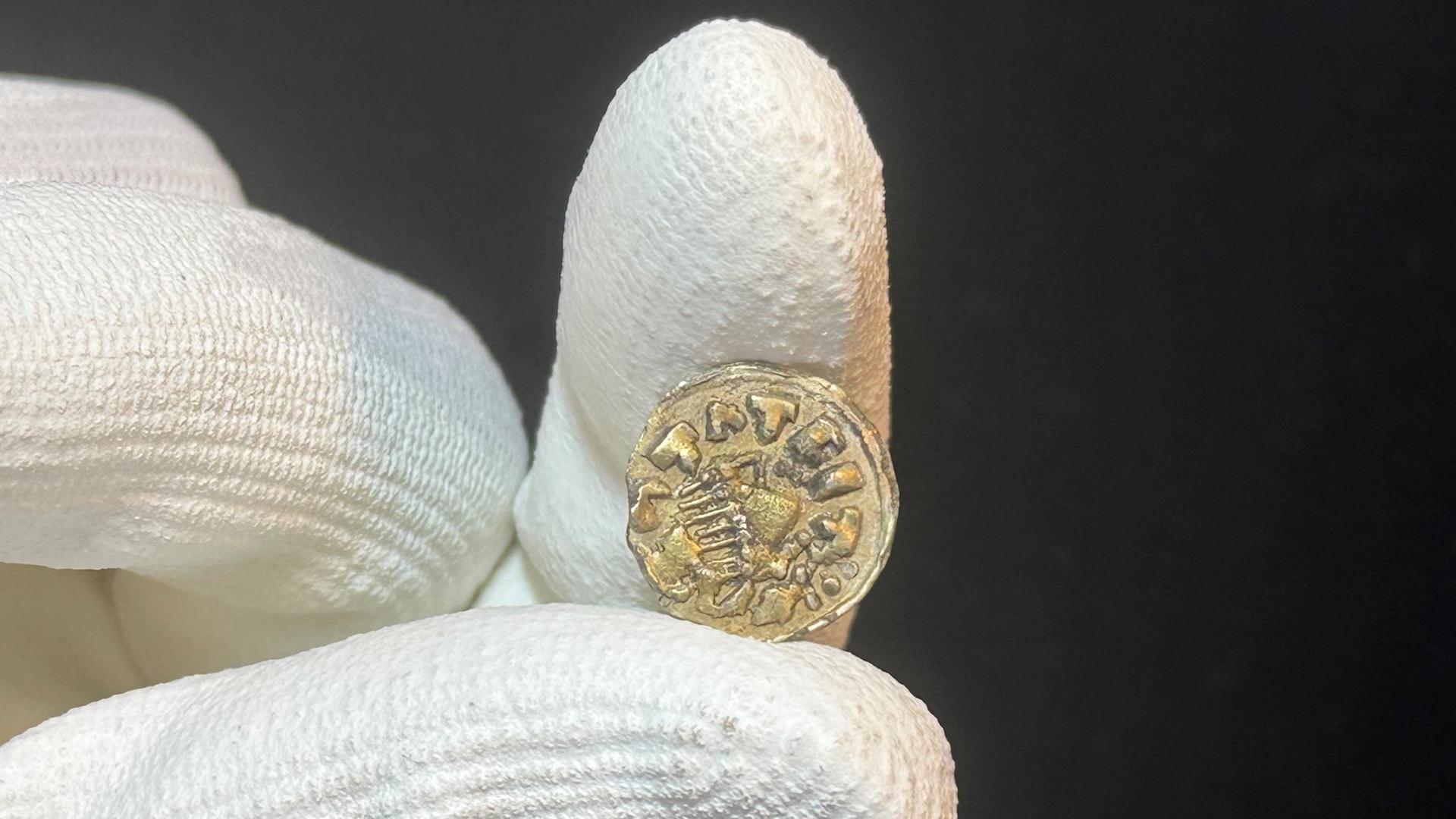 Halle: Eine Hand hält eine Goldmünze. Halle: Eine Hand hält eine Goldmünze.