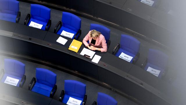 Vogelperspektive auf eine einzelne Abgeordnete, die im Plenarsaal des Bundestags sitzt.