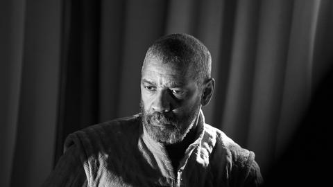 Der Schauspieler Denzel Washington spielt Macbeth, sein Gesicht ist im Halbschatten, er blickt nach links. Die Aufnahme ist in Schwarzweiß. 