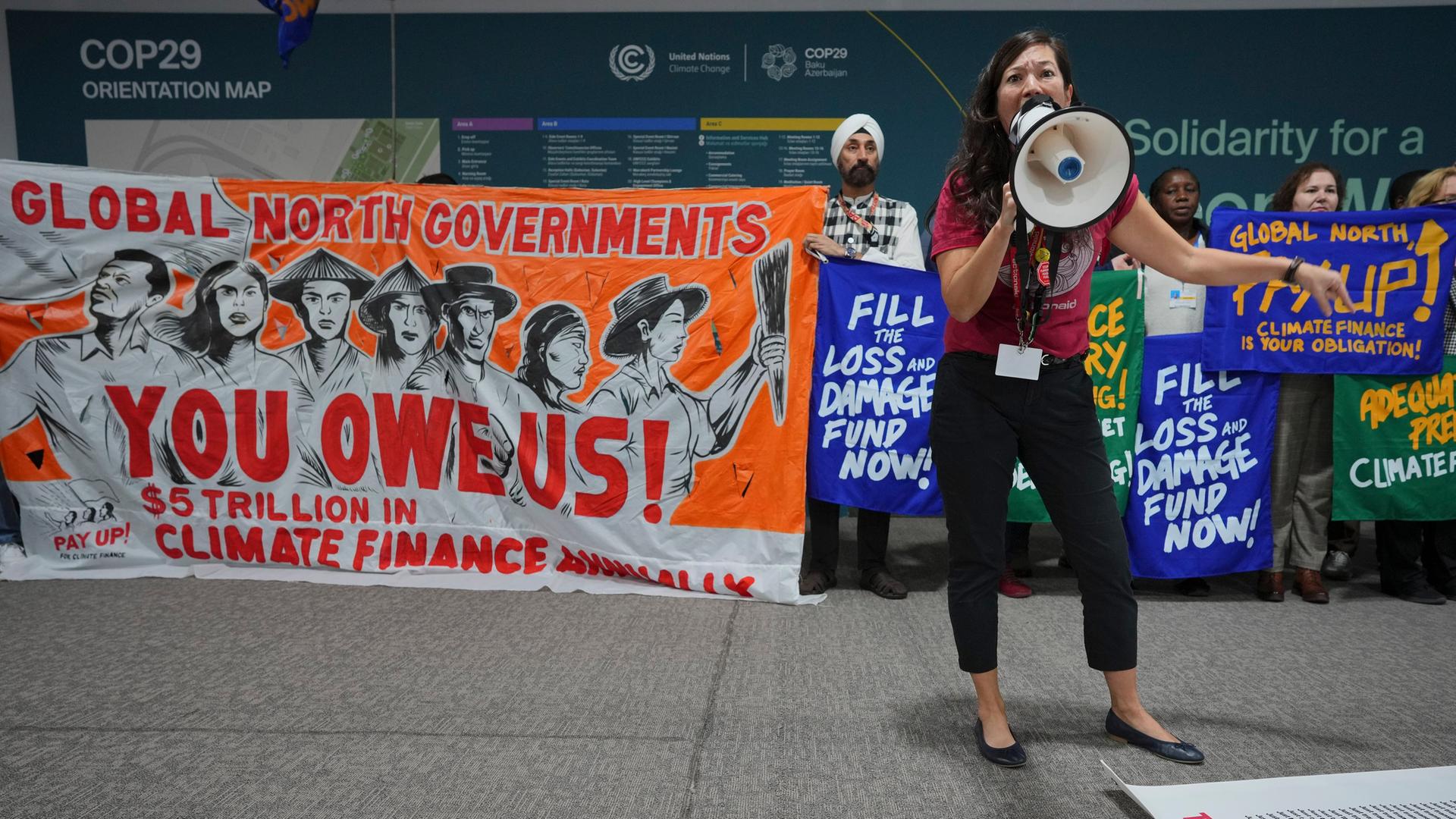 Klimaschutz-Aktivistin Teresa Anderson spricht während einer Demonstration für die Finanzierung von Klimaschutz-Maßnahmen während der Klimaschutzkonferenz COP29 in Baku in ein Megafon.