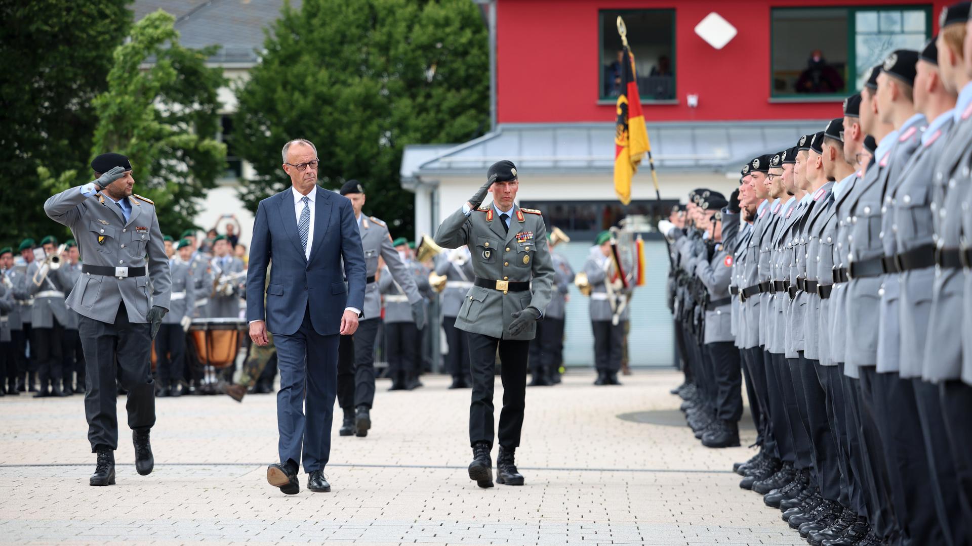 Bundeskanzler Merz geht zwischen zwei Bundeswehrsoldaten an einer Reihe von uniformierten Rekruten vorbei. Bundeskanzler Merz geht zwischen zwei Bundeswehrsoldaten an einer Reihe von uniformierten Rekruten vorbei.