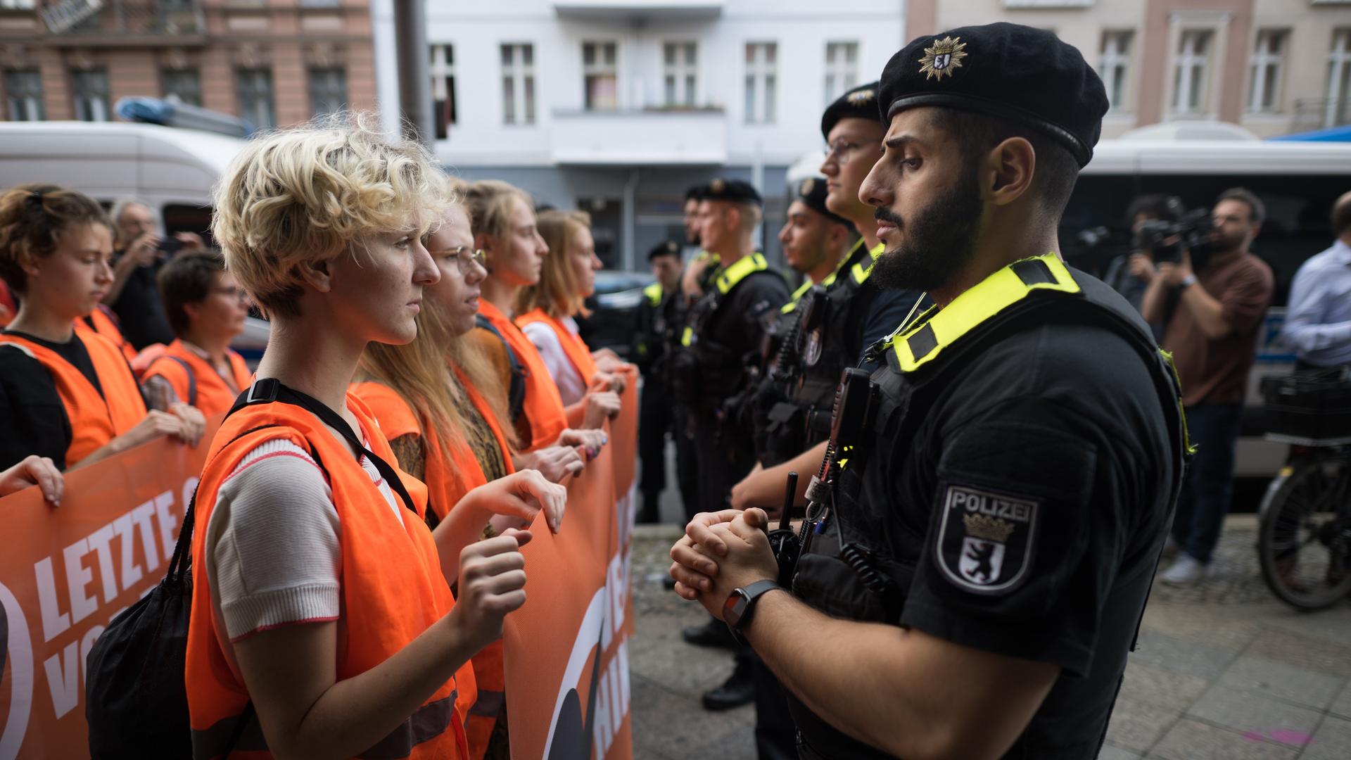 Polizeibeamte stehen zu Beginn eines Protestmarsches der Klimaschutzgruppe Letzte Generation vor Teilnehmern der Demonstration. Der Protestmarsch ist der Beginn neuer Blockaden und Protest in der Hauptstadt.