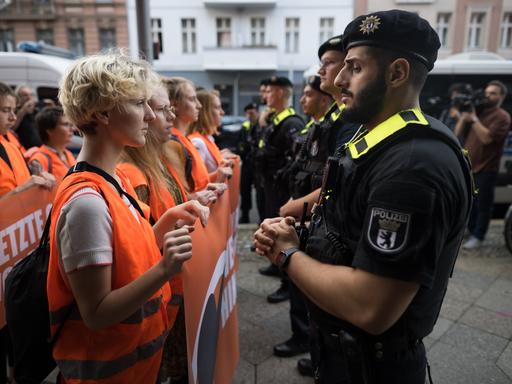 Polizeibeamte stehen zu Beginn eines Protestmarsches der Klimaschutzgruppe Letzte Generation vor Teilnehmern der Demonstration. Der Protestmarsch ist der Beginn neuer Blockaden und Protest in der Hauptstadt.