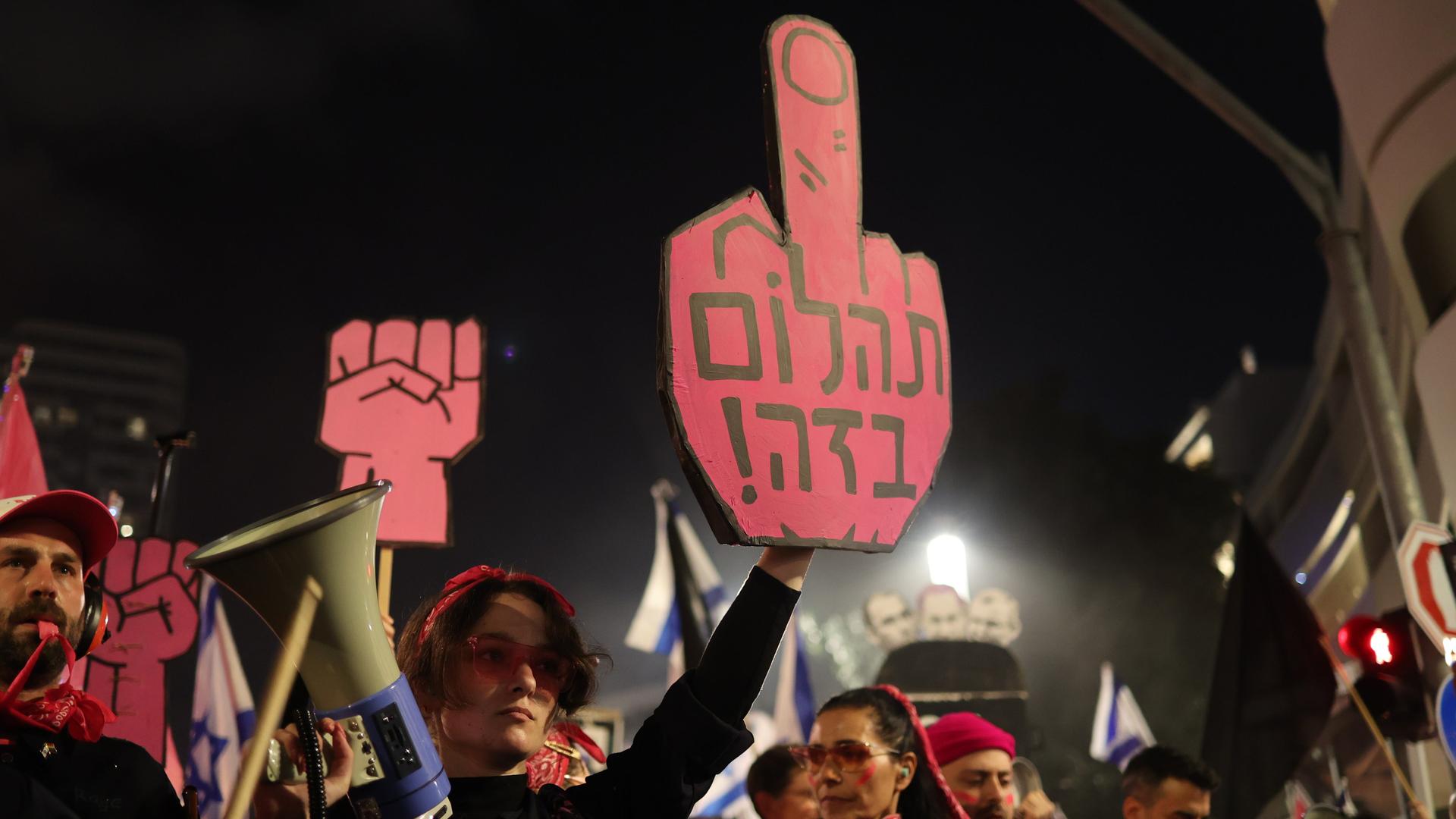 Israelische Demonstranten halten Plakate und Fahnen während einer Demonstration gegen die Regierung. Israelische Demonstranten halten Plakate und Fahnen während einer Demonstration gegen die Regierung.