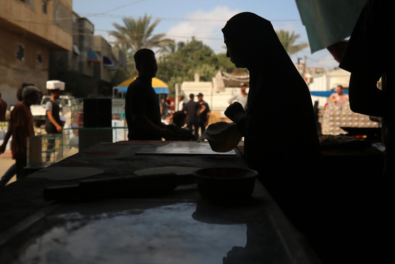 Eine vertriebene palästinensische Frau bereitet am 2. Juli 2024 inmitten des anhaltenden Konflikts in den palästinensischen Gebieten zwischen Israel und der Hamas auf der Straße im Gazastreifen Fladenbrot zu.