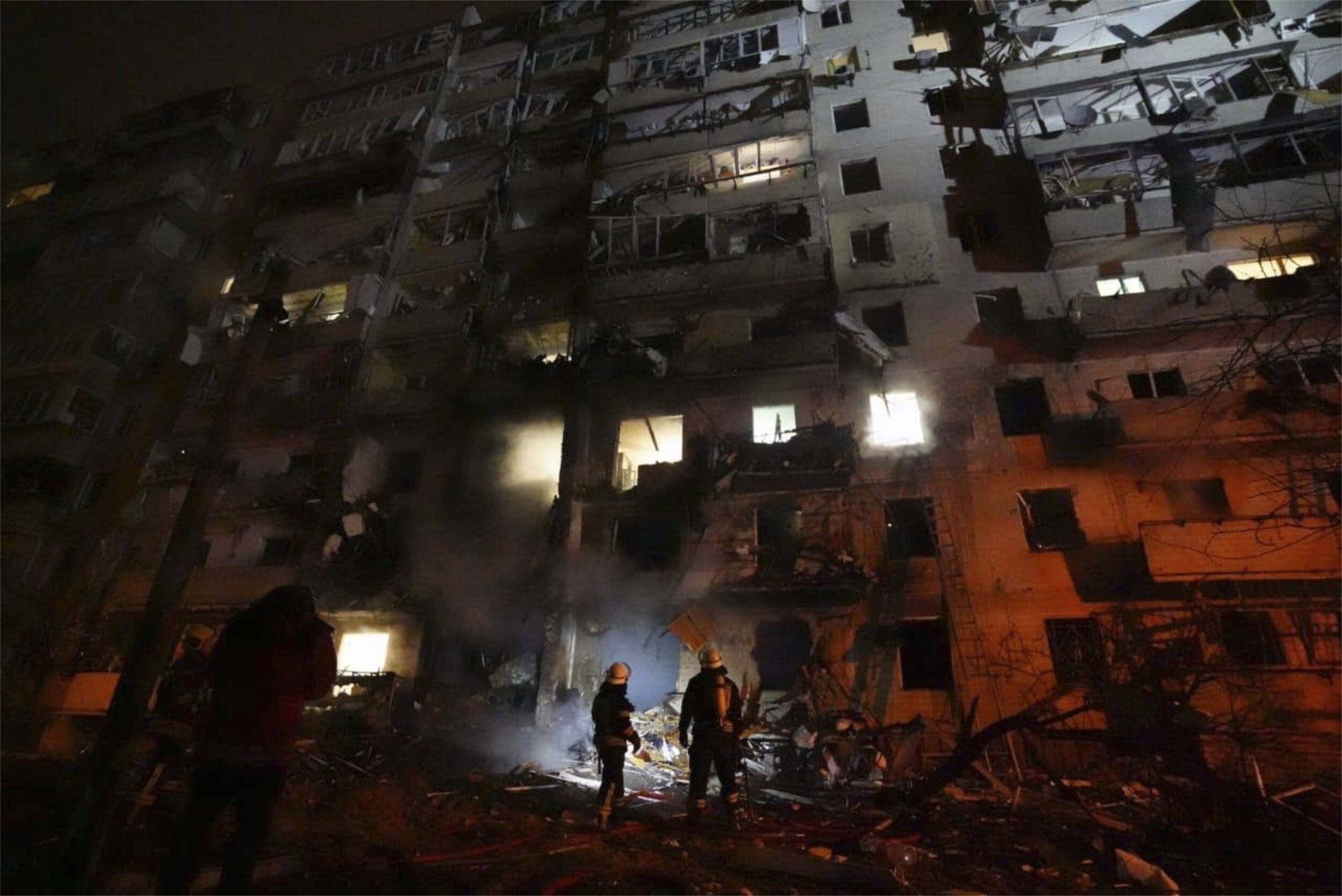 Zwei Feuerwehrleute stehen vor einem Wohnhaus in Kyiv, 24.02.2022