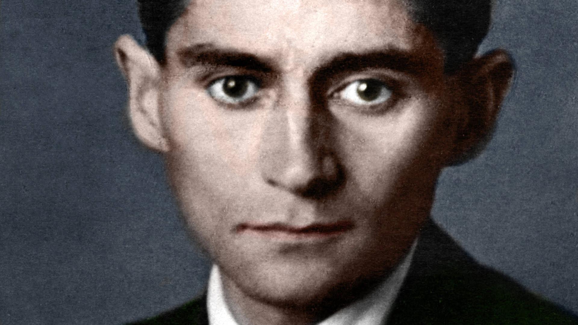 Ein nachkoloriertes Portrait von Franz Kafka. Er trägt einen Anzug mit Krawatte
