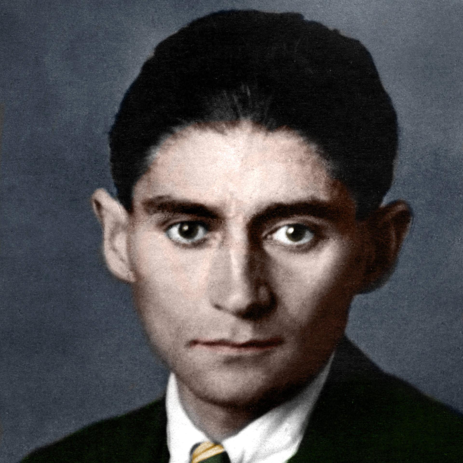 Ein nachkoloriertes Portrait von Franz Kafka. Er trägt einen Anzug mit Krawatte