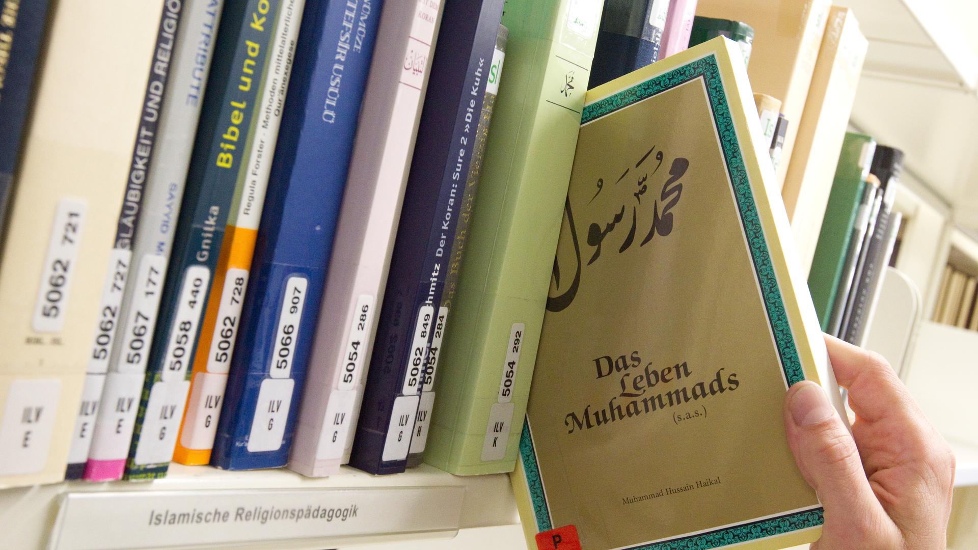 Das Buch "Das Leben Muhammads" wird in der Bibliothek der Universität Osnabrück aus einem Bücherregal gezogen. Weitere Bücher stehen im Regal.