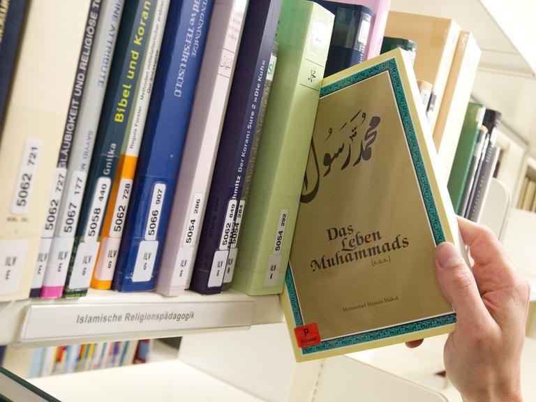Das Buch "Das Leben Muhammads" wird in der Bibliothek der Universität Osnabrück aus einem Bücherregal gezogen. Weitere Bücher stehen im Regal.