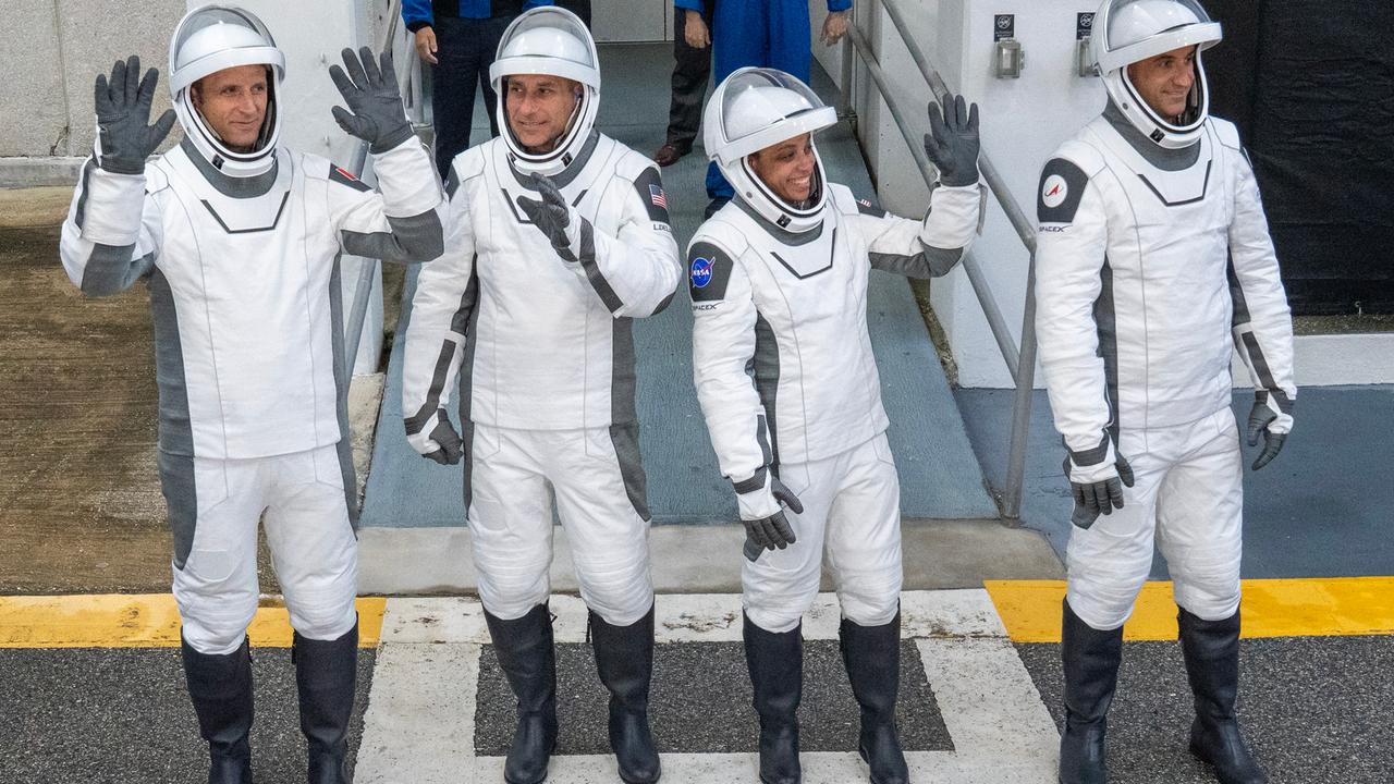 Das Bild zeigt die NASA-Astronautin Jessica Watkins und ihre Kollegen Luke Delaney, Joshua Kutryk und Sergey Teteryatnikov in weißen Raumanzügen mit Helm. Sie winken fröhlich in die Menge.
      