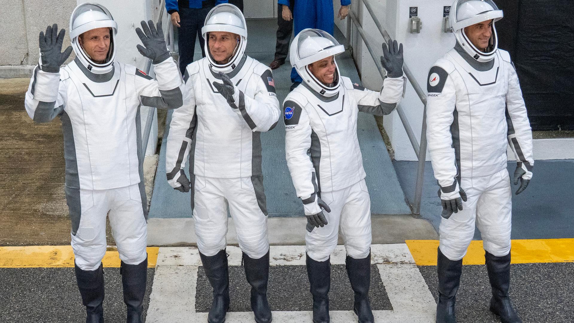 Das Bild zeigt die NASA-Astronautin Jessica Watkins und ihre Kollegen Luke Delaney, Joshua Kutryk und Sergey Teteryatnikov in weißen Raumanzügen mit Helm. Sie winken fröhlich in die Menge.
Das Bild zeigt die NASA-Astronautin Jessica Watkins und ihre Kollegen Luke Delaney, Joshua Kutryk und Sergey Teteryatnikov in weißen Raumanzügen mit Helm. Sie winken fröhlich in die Menge.
