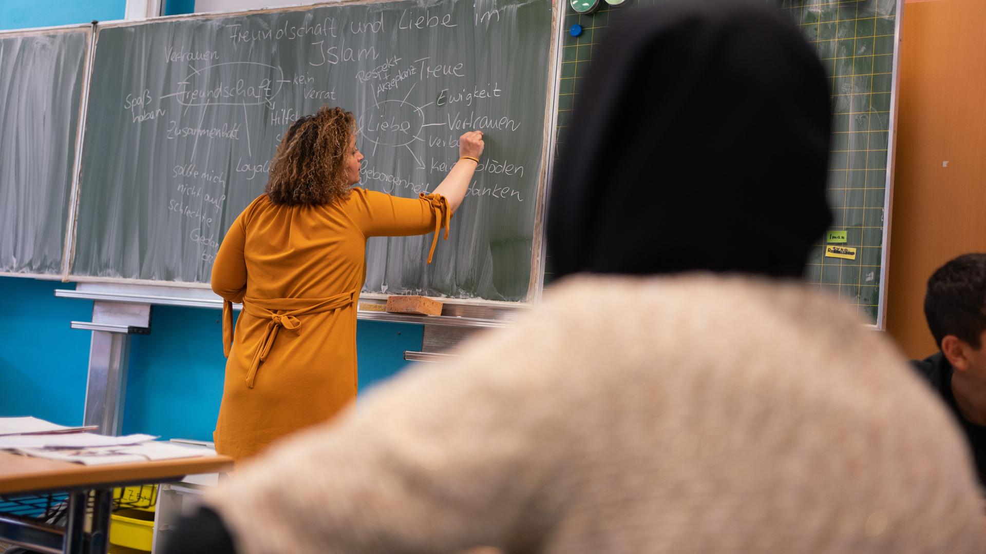 Die Lehrerin Nurdagül Ceri schreibt beim Islamunterricht in der Frankfurter Ernst-Reuter-Schule mit Schülern einer siebten Klasse Sätze an die Tafel.